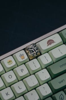 Close-up of a custom artisan keycap on a stylish gaming keyboard with green keys.
