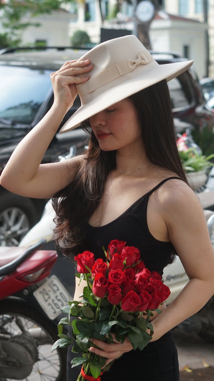 Woman Putting Beige Fedora Hat On Head