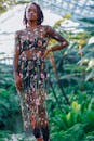 一位自信的女人身着透明花卉连衣裙，在生机勃勃的温室里摆着姿势