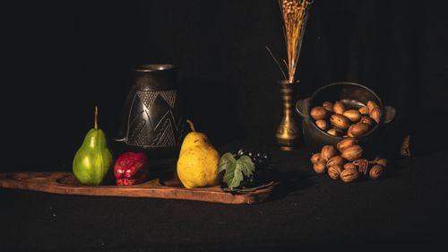 Free Artistic still life of pears, grapes, pecans, and a vase on a black background. Stock Photo