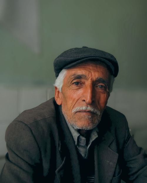 Free A detailed portrait of an elderly man with a gray mustache and cap, exuding elegance. Stock Photo