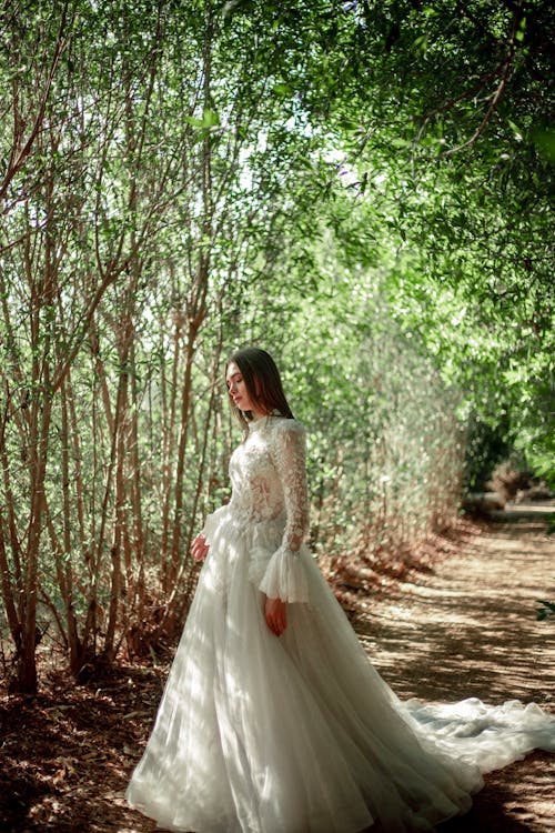Woman in Long Wedding Dress Walking through the Forest