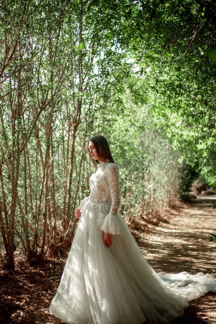 A graceful woman in a long white wedding dress strolls through a verdant forest path in Cairo, capturing elegance and serenity.