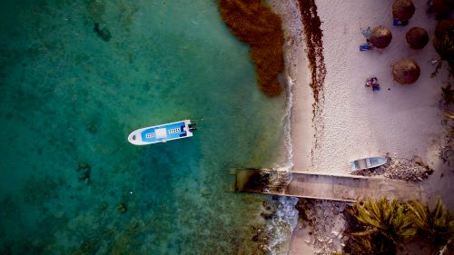 Free Aerial photo of a turquoise sea, moored boat, and sandy shore in Paa Mul, México. Stock Photo