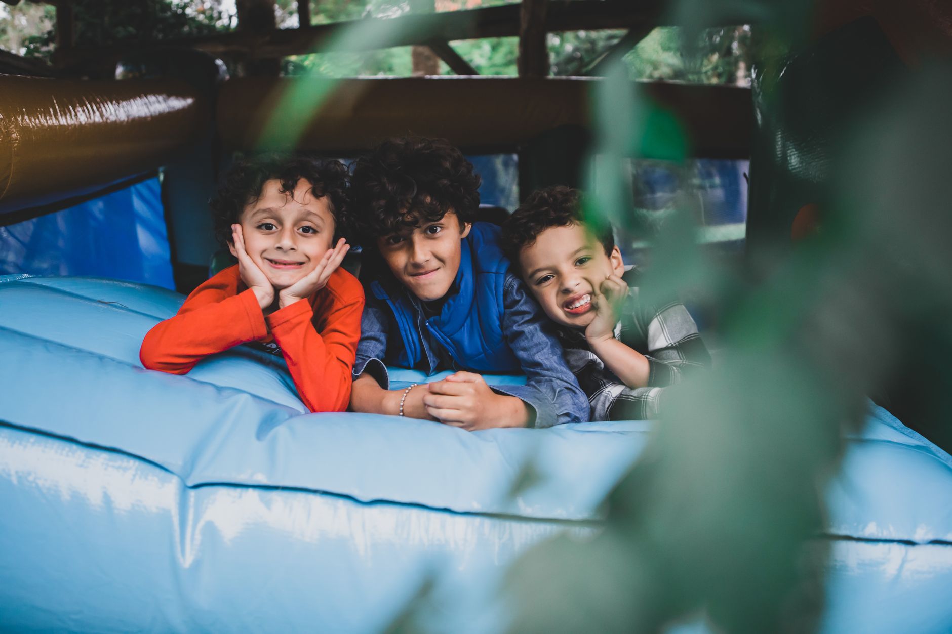 trampoline rental for parties egypt — Three smiling children enjoy a bouncy time on a trampoline, embodying youthful joy and