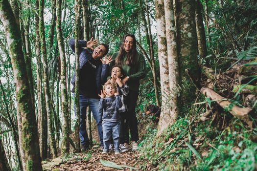 Playful family enjoying a silly moment amidst a vibrant green forest trail.