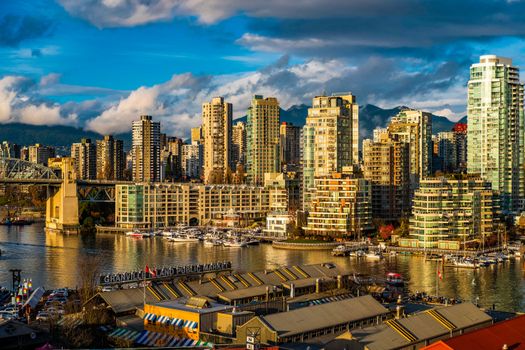 Beautiful view of Vancouver's modern skyline and Granville Island public market at sunset.