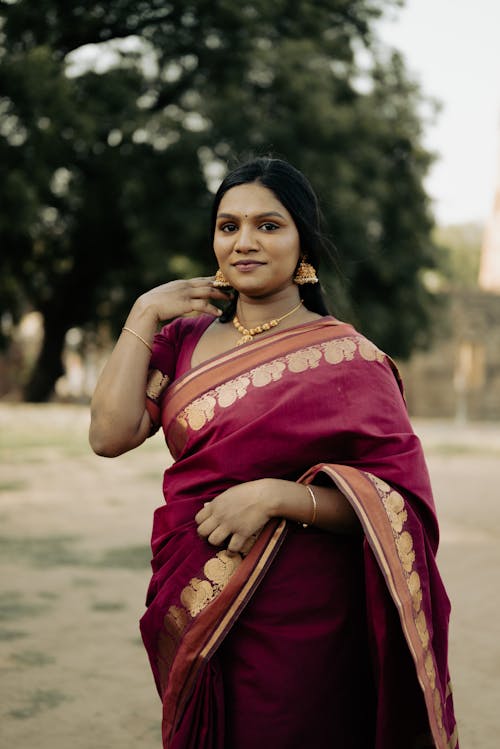 Photo of a Woman Wearing Red Sari Standing against a Tree