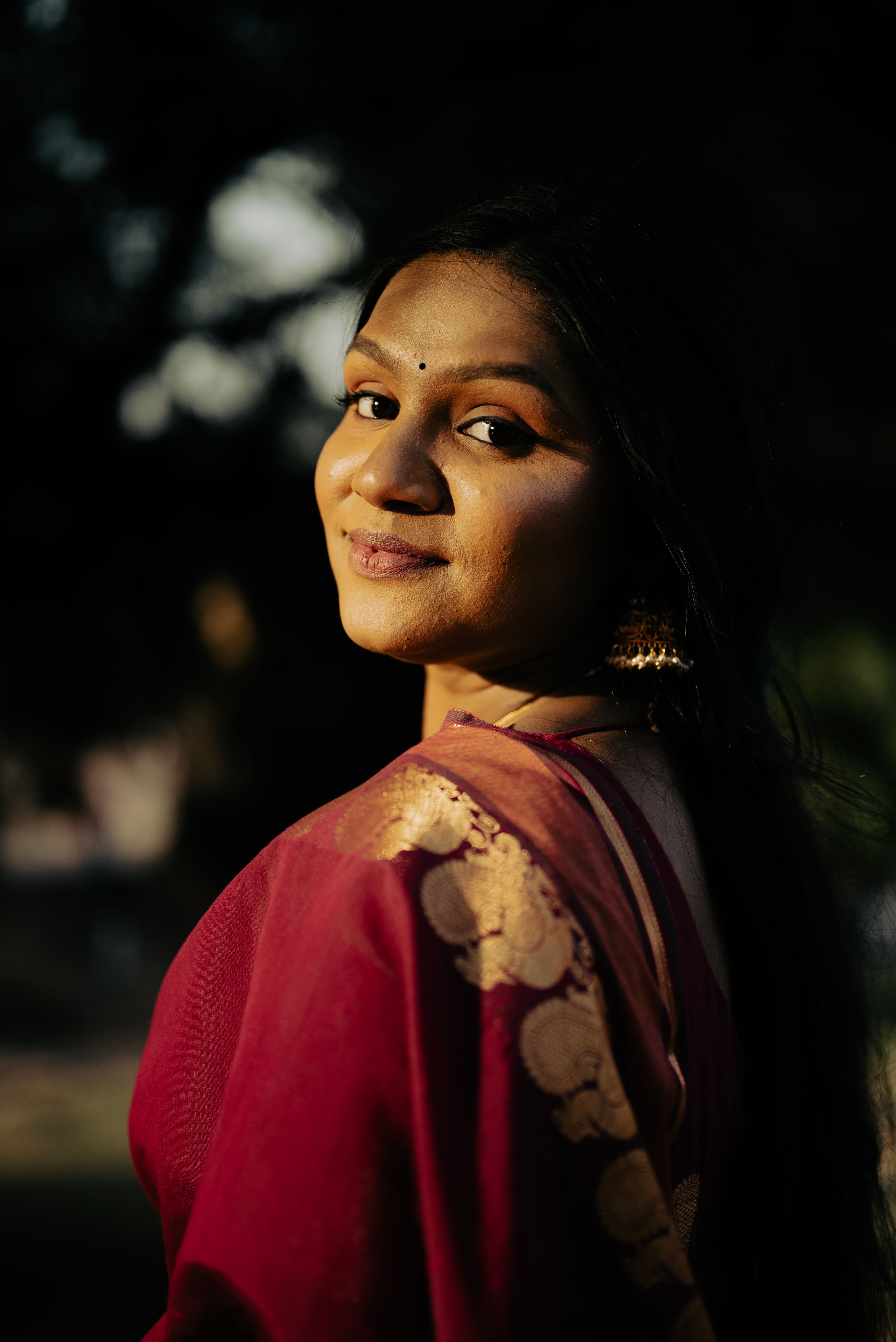 Beautiful portrait of a smiling woman in traditional Indian attire with golden sunlight.