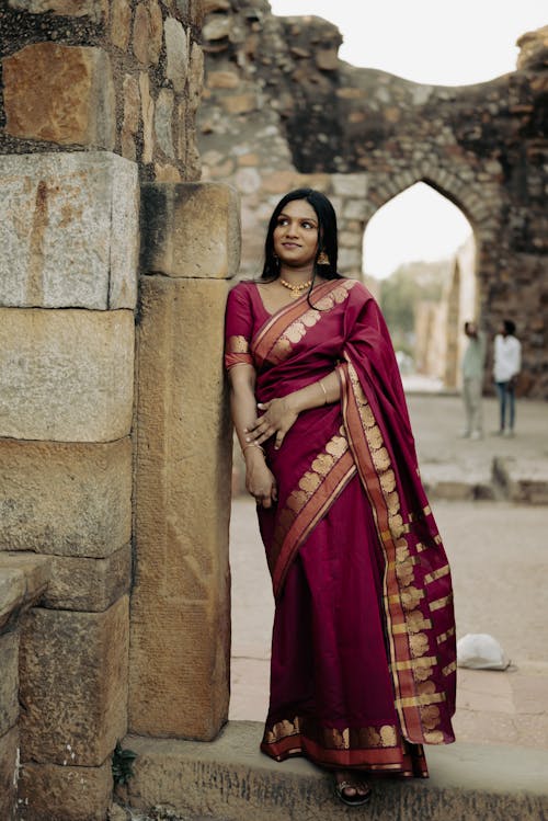Beautiful Indian Woman in Traditional Clothing Leaning against a Building Facade 