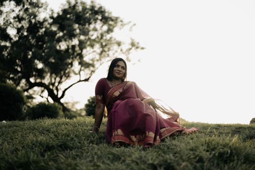 Free Beautiful South Asian woman in a sari, sitting on grass in natural light, embodying tradition and elegance. Stock Photo