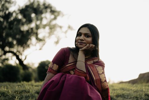 Free A serene portrait of a South Asian woman wearing a traditional sari, seated outdoors at sunset. Stock Photo