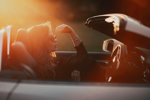 Free A woman enjoying a peaceful moment in a convertible during sunset. Stock Photo