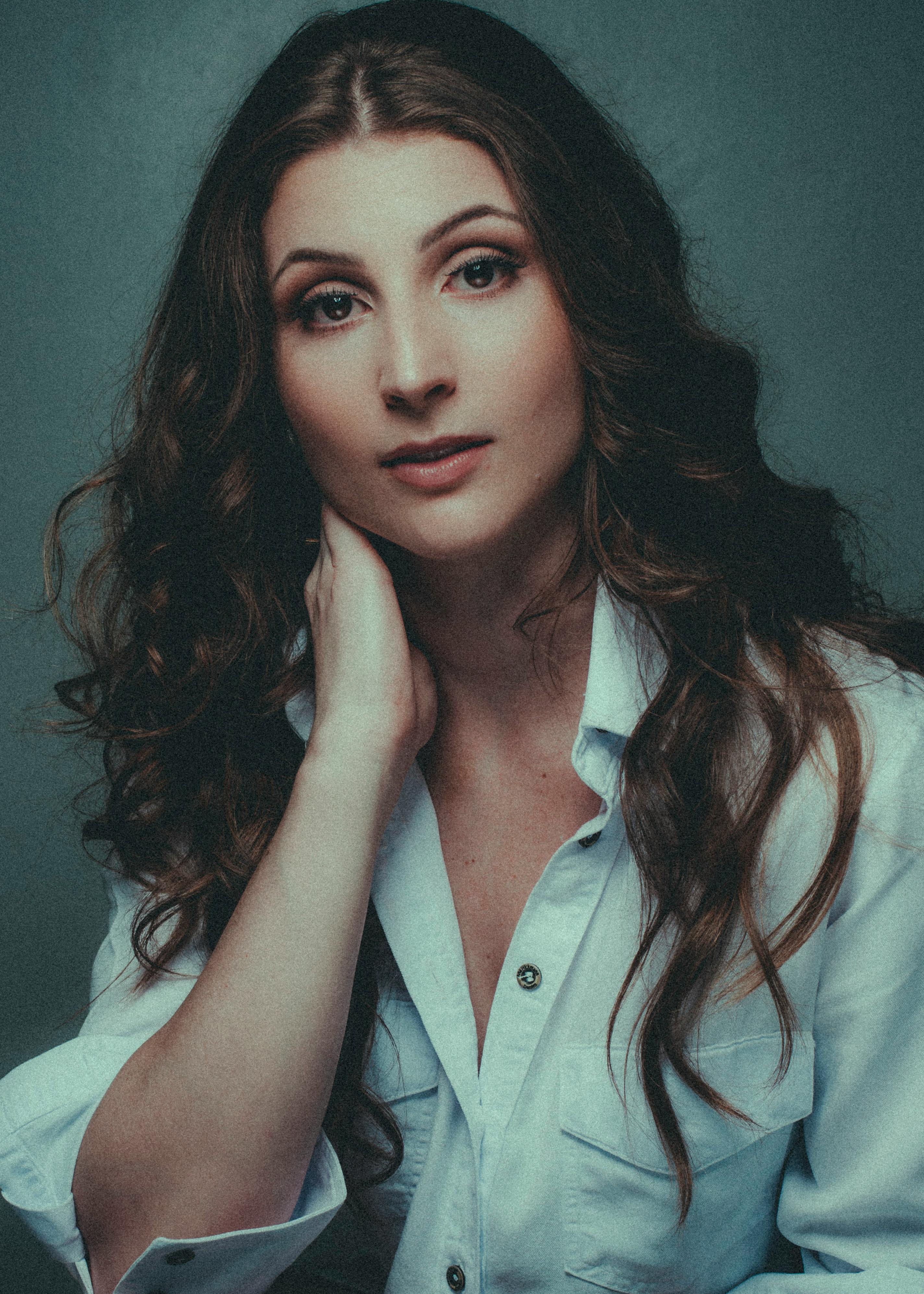 Beautiful portrait of a woman with long hair in a stylish white blouse, looking serene.