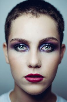 Striking portrait showcasing bold makeup and short hair against a studio backdrop.