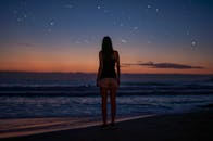 黄昏时分，一名女子在海滩边凝视星空的剪影