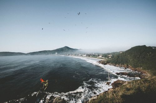 Free A breathtaking aerial view of a coastal landscape with mountains and birds flying above. Stock Photo