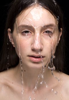 Artistic close-up portrait of a woman's face with water splashing over it, creating a refreshing effect.