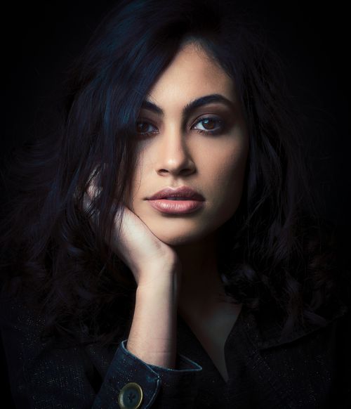 Free Close-up portrait of a woman with thoughtful expression, captured in a studio with dark background. Stock Photo