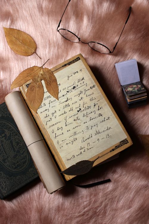 A forest-green reading journal surrounded by art props and vintage papers