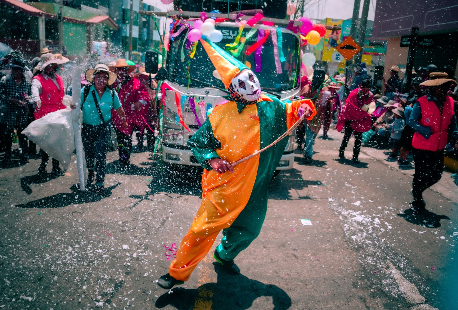 Desfile en una calle con gente disfrazada de colores vivos y confeti en el aire