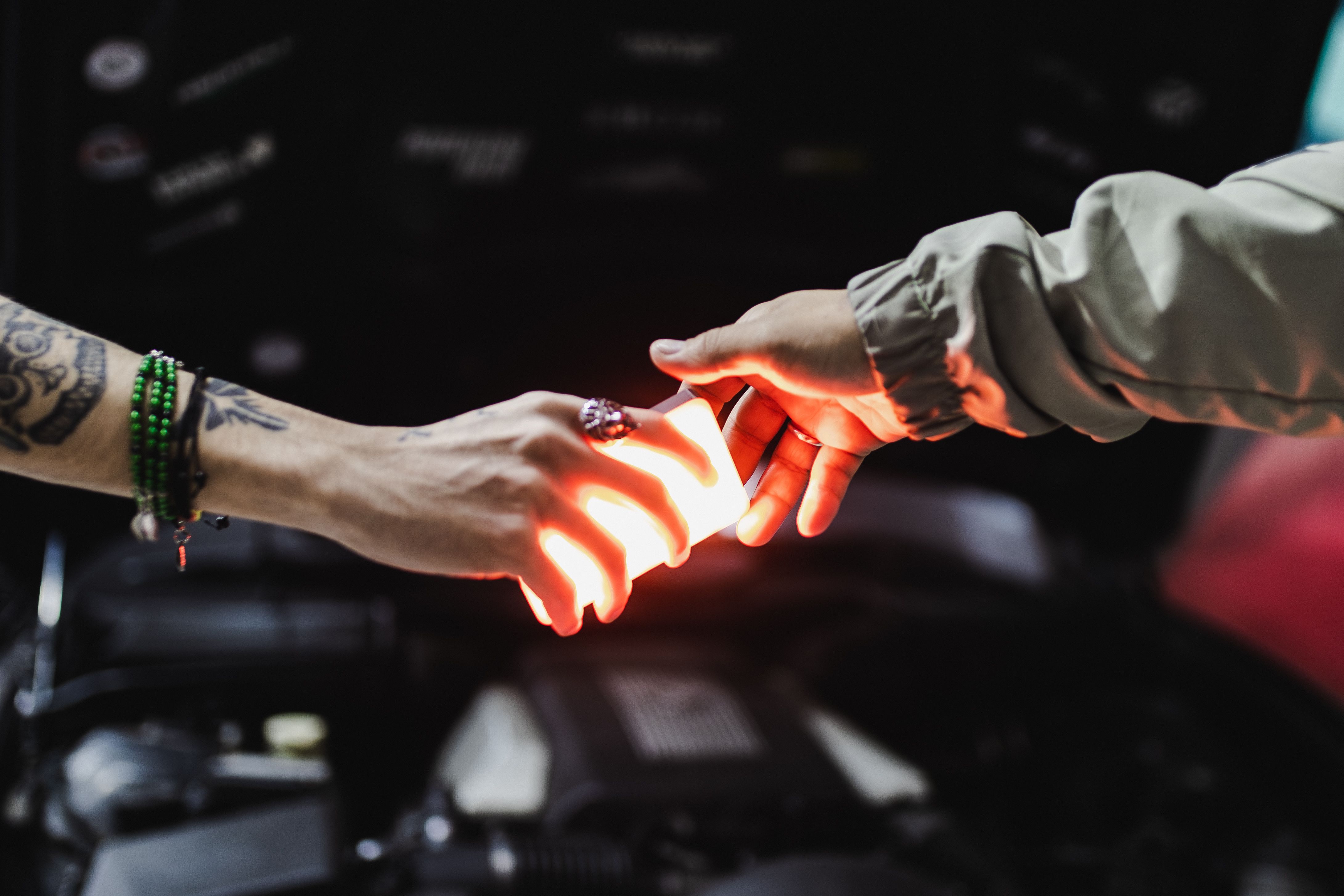 Two hands exchanging bright light in dark setting · Free Stock Photo