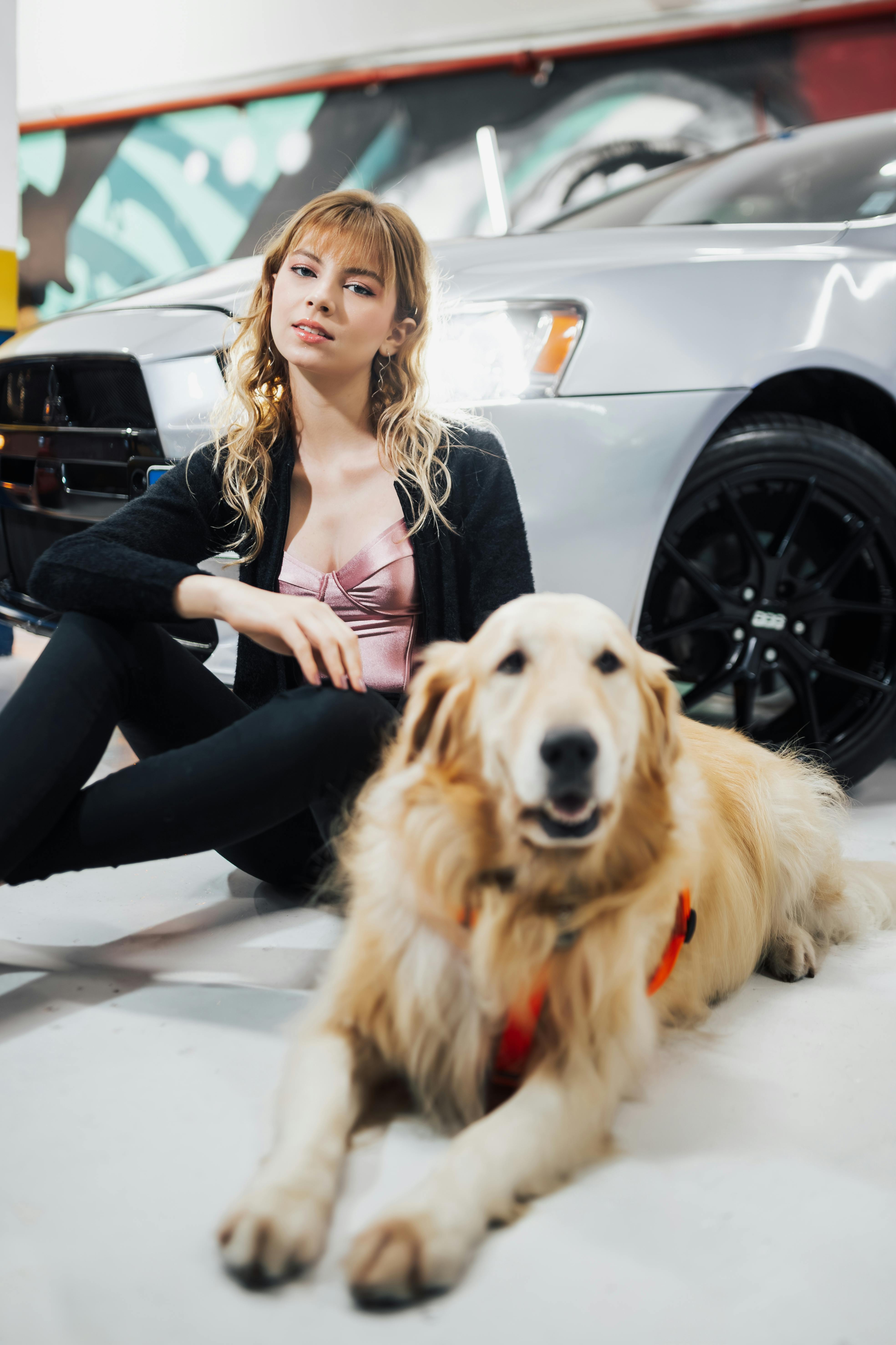 woman sitting with dog by car