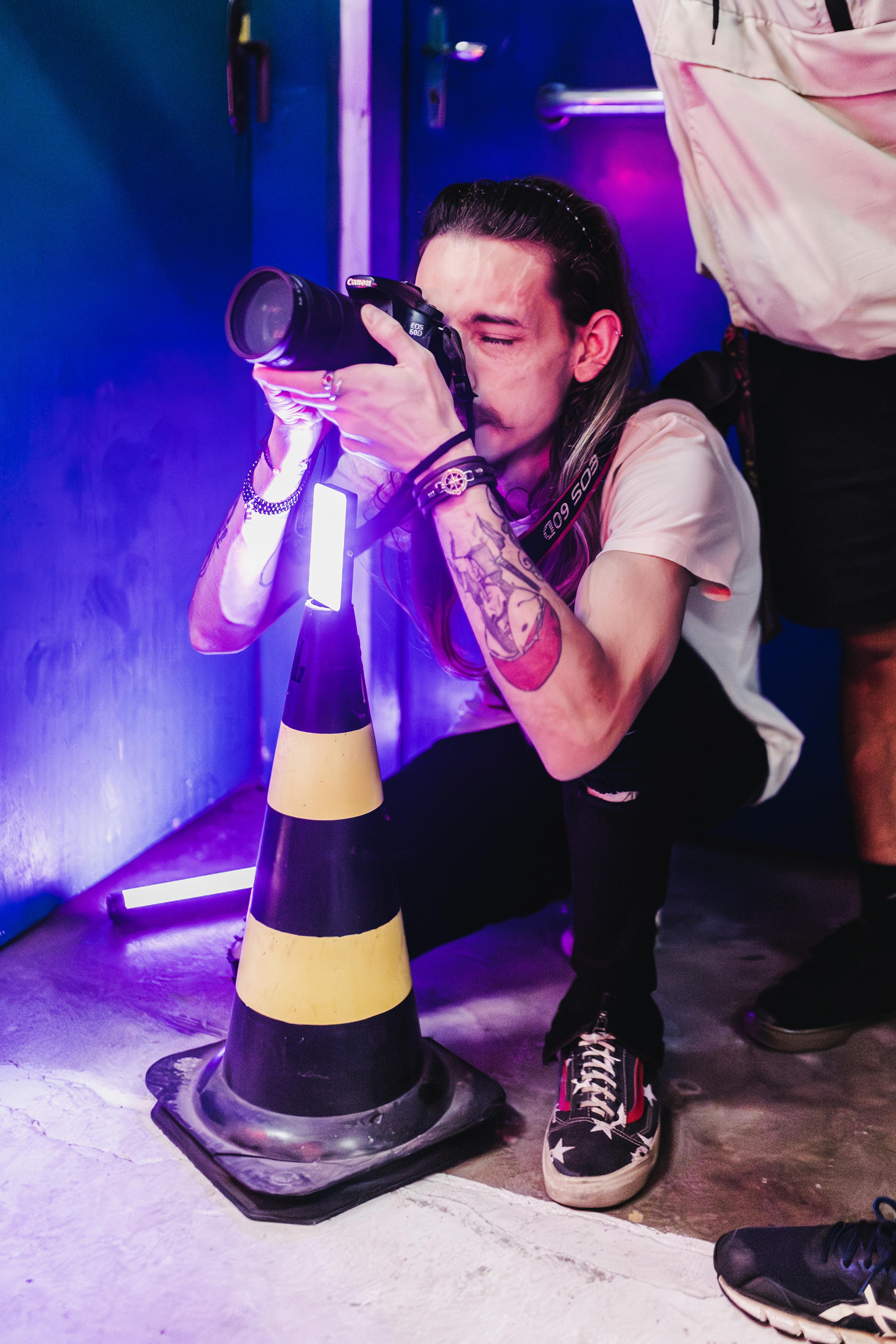 Free A tattooed photographer captures shots in a vibrant indoor studio setting. Stock Photo