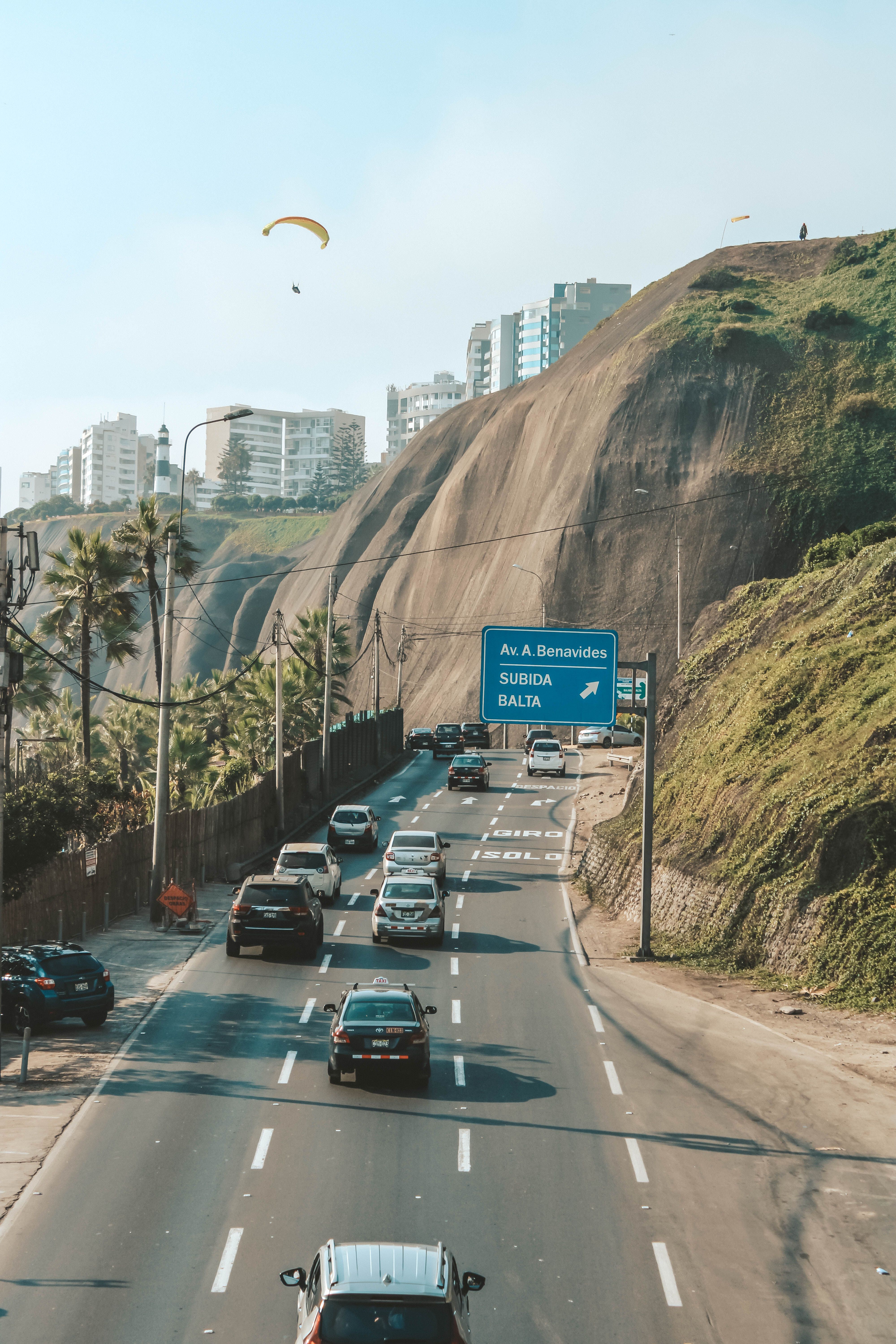 View of traffic on Av. Benavides in Lima with cliffs and paragliders in the background.