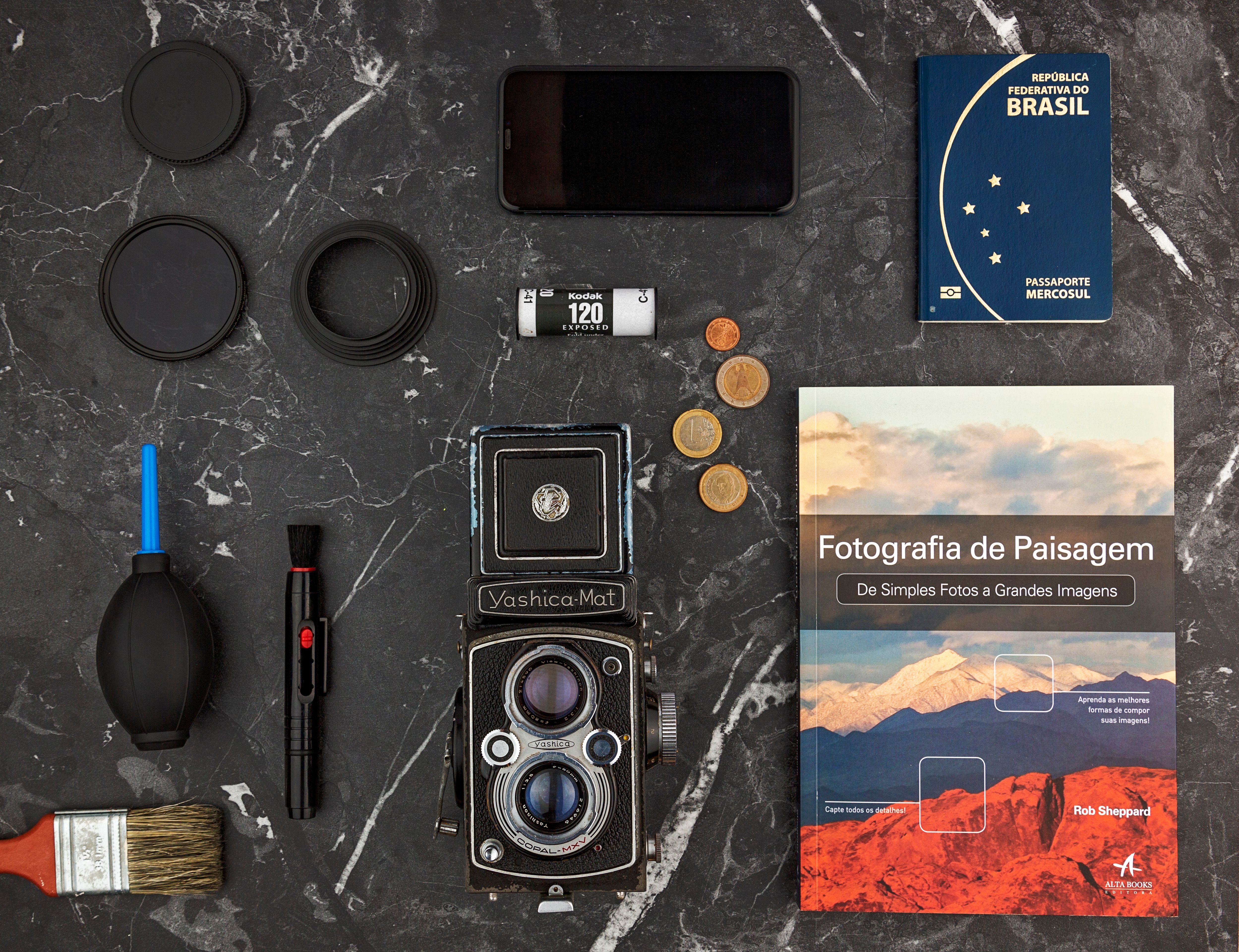 Vintage camera, photography book, and accessories on dark marble background.