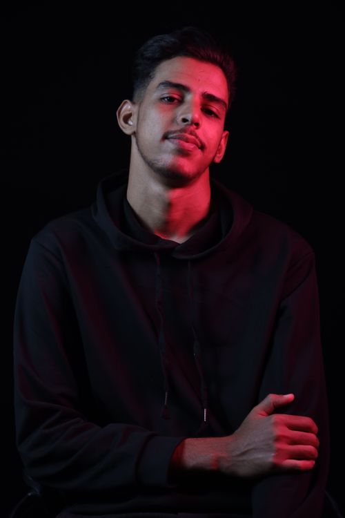Free Close-up portrait of a confident man in a black hoodie against a dark background. Stock Photo