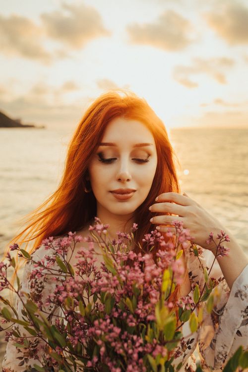 Free A serene portrait of a woman with flowers at sunset, showcasing the vibrant summer beauty of a Turkish beach. Stock Photo