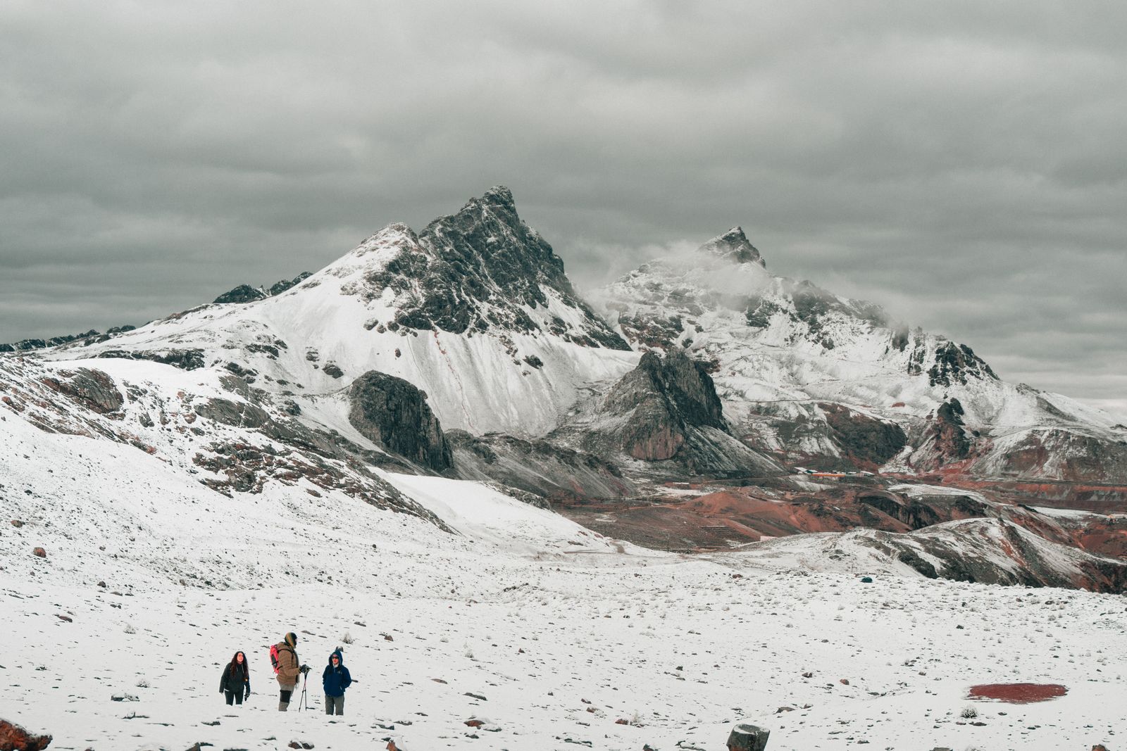 Trekkers on a high snow-dusted trail in the Peruvian Andes