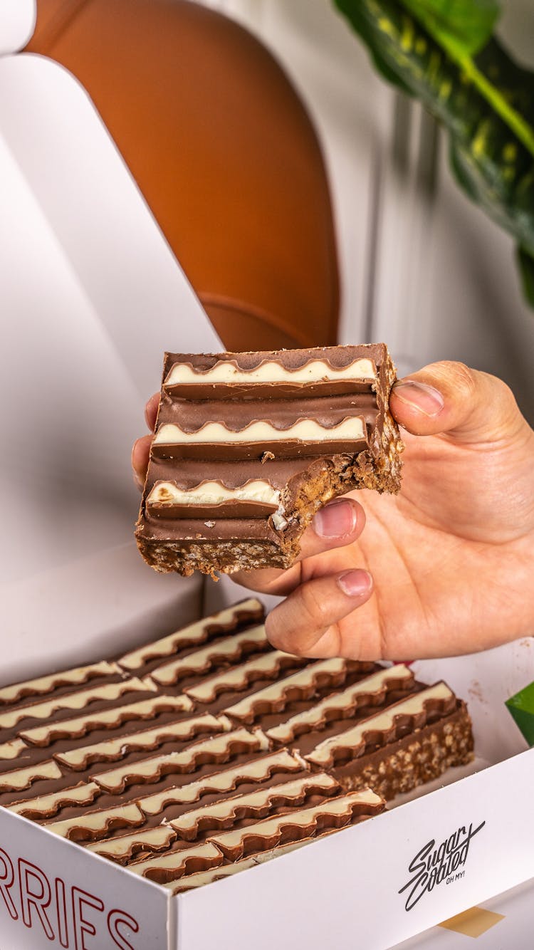 Closeup Of A Hand Holding A Slice Of A Layered Cake