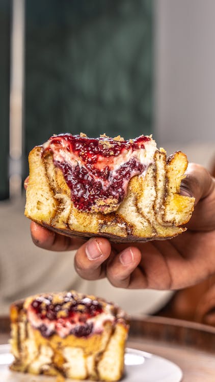 Closeup of a Hand Holding a Swirl Cake with Raspberry Jam