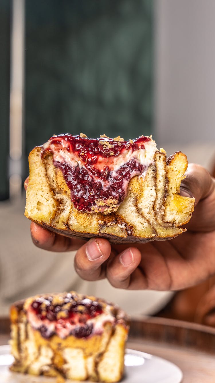 Closeup Of A Hand Holding A Swirl Cake With Raspberry Jam