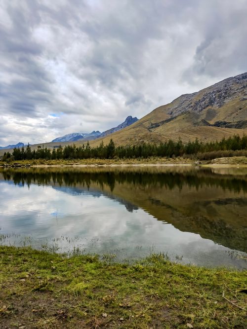 Free Beautiful overcast landscape of Huaraz with reflecting mountains and a serene river. Stock Photo