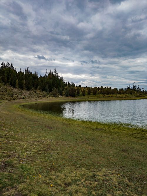 Free Serene mountain lake surrounded by lush greenery and cloudy skies in Huaraz, Peru. Stock Photo