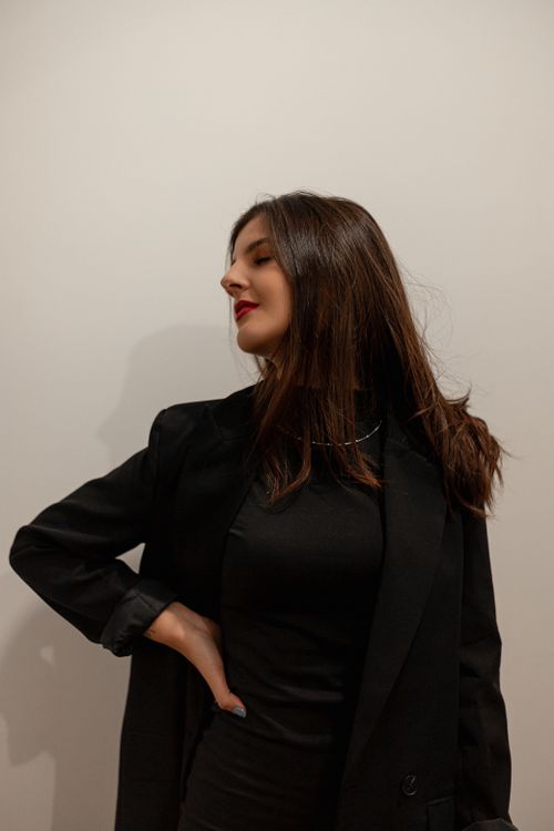 Free Young woman in a sleek black outfit posing confidently indoors, showcasing modern fashion. Stock Photo