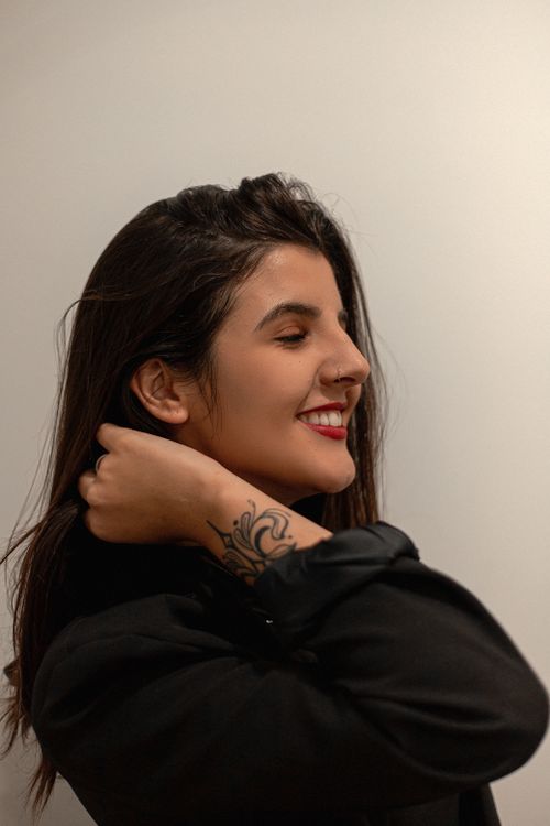 Free A smiling woman elegantly posing with a visible tattoo, eyes closed, in Brazil. Stock Photo