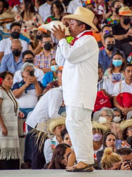 Musician in traditional attire plays at a vibrant festival crowd in Oaxaca, Mexico.