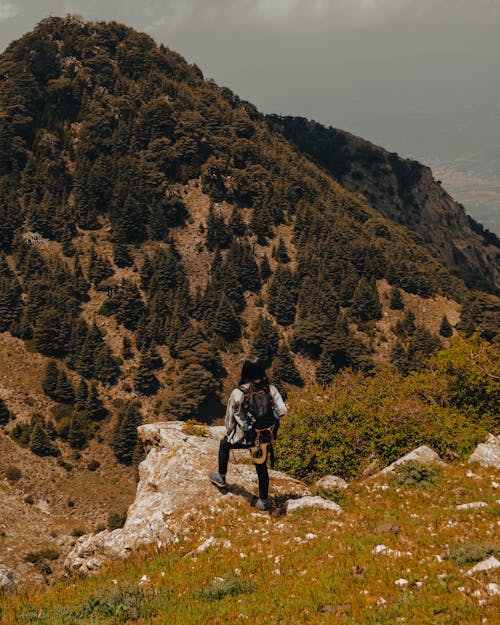 Photo of a Young Woman with a Backpack in the Mountains