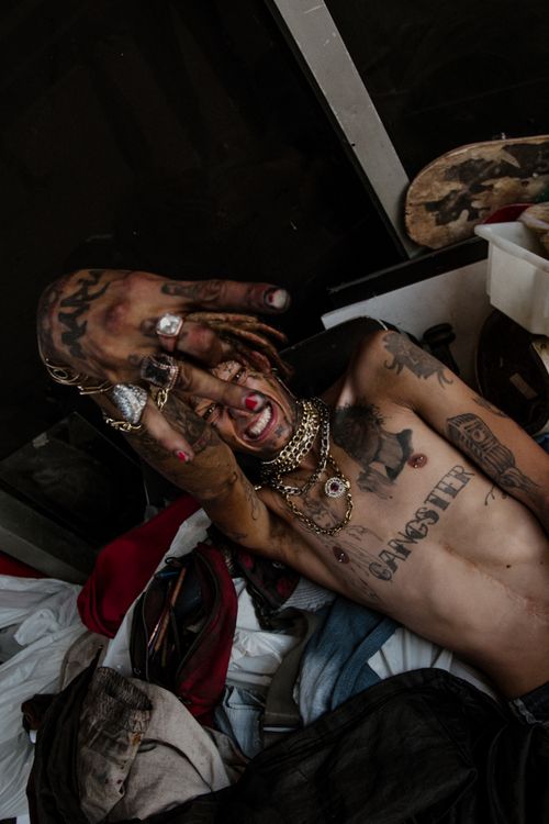 Free Shirtless man with dreadlocks and tattoos lies amidst urban decay, Jawa Brasil. Stock Photo
