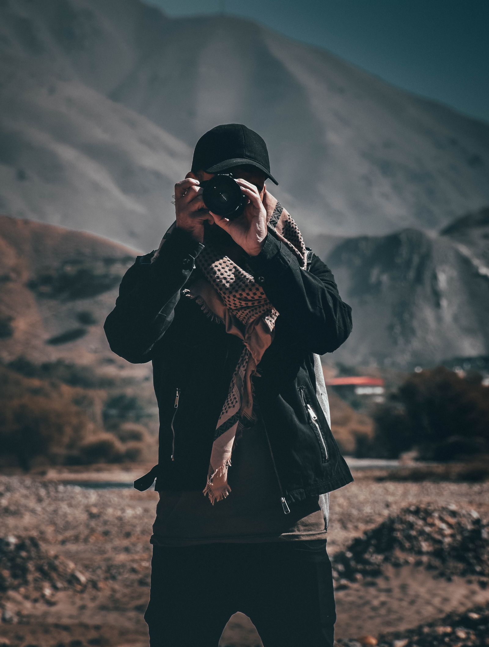 A photographer standing in mountain terrain with a camera