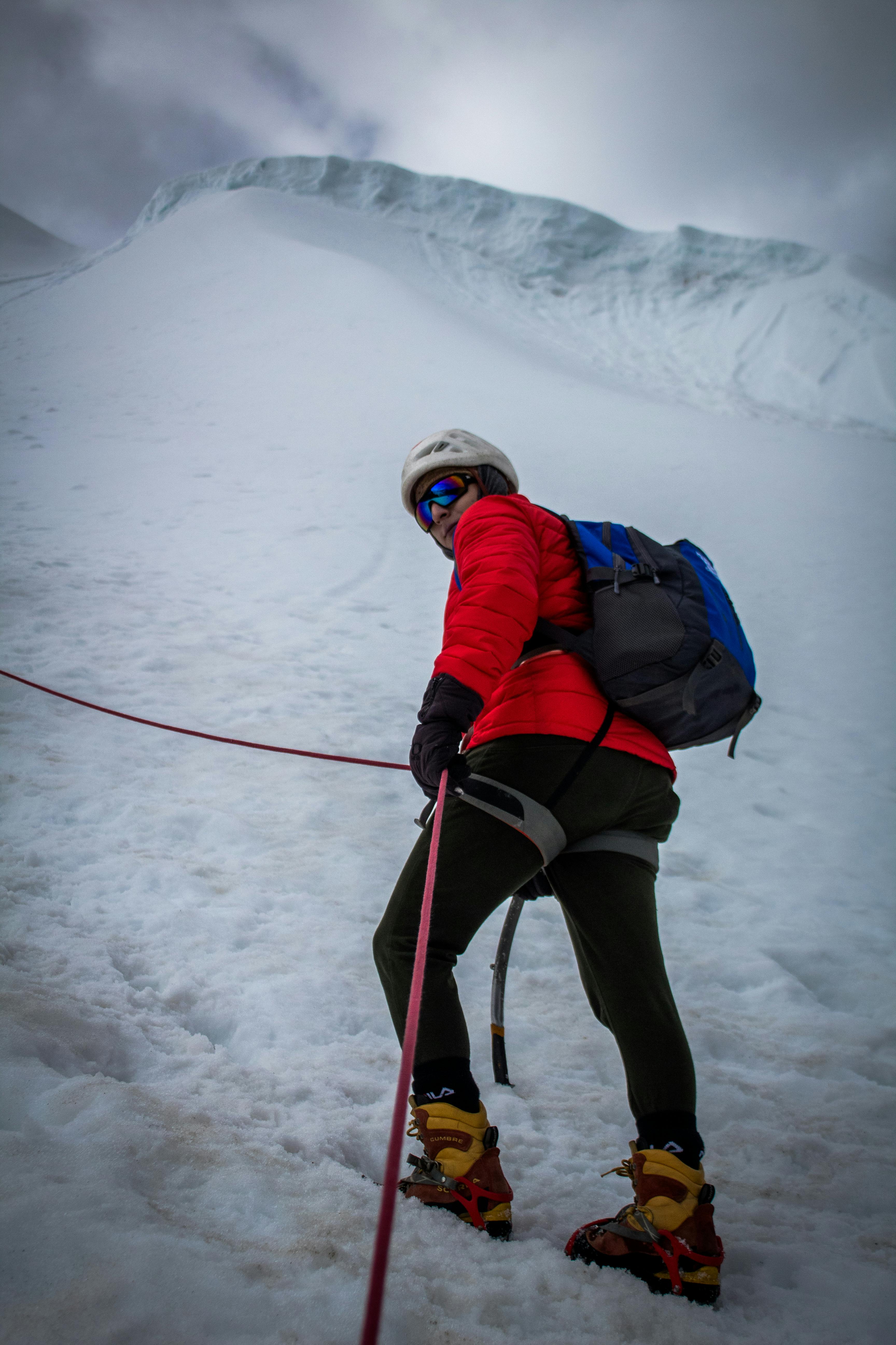 Prescription Goggle Inserts - Adventurous mountaineer climbing a snowy mountain with ice axe and ropes during winter.