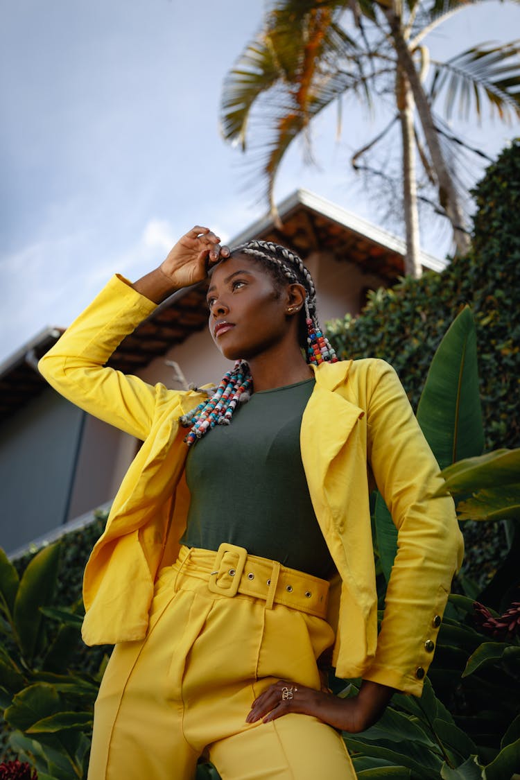 Low Angle Shot Of A Young Woman In A Yellow Outfit Posing Outside 