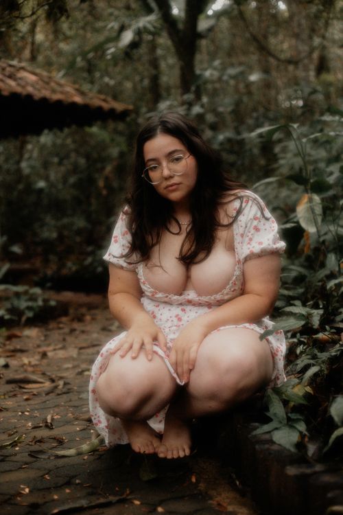 Free A young woman crouches barefoot in a lush forest in Belo Horizonte, exuding natural beauty. Stock Photo