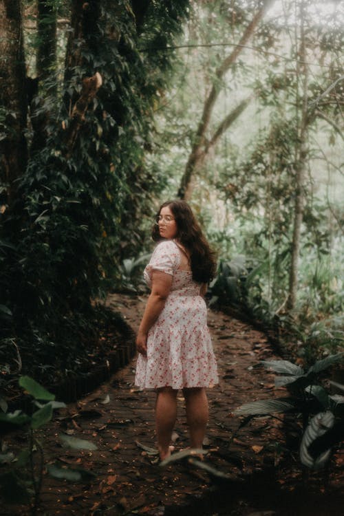 Young Woman in a Dress Standing in the Forest Barefoot