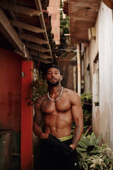Portrait of a muscular, tattooed man standing topless in an urban alley in Belo Horizonte, Brazil.