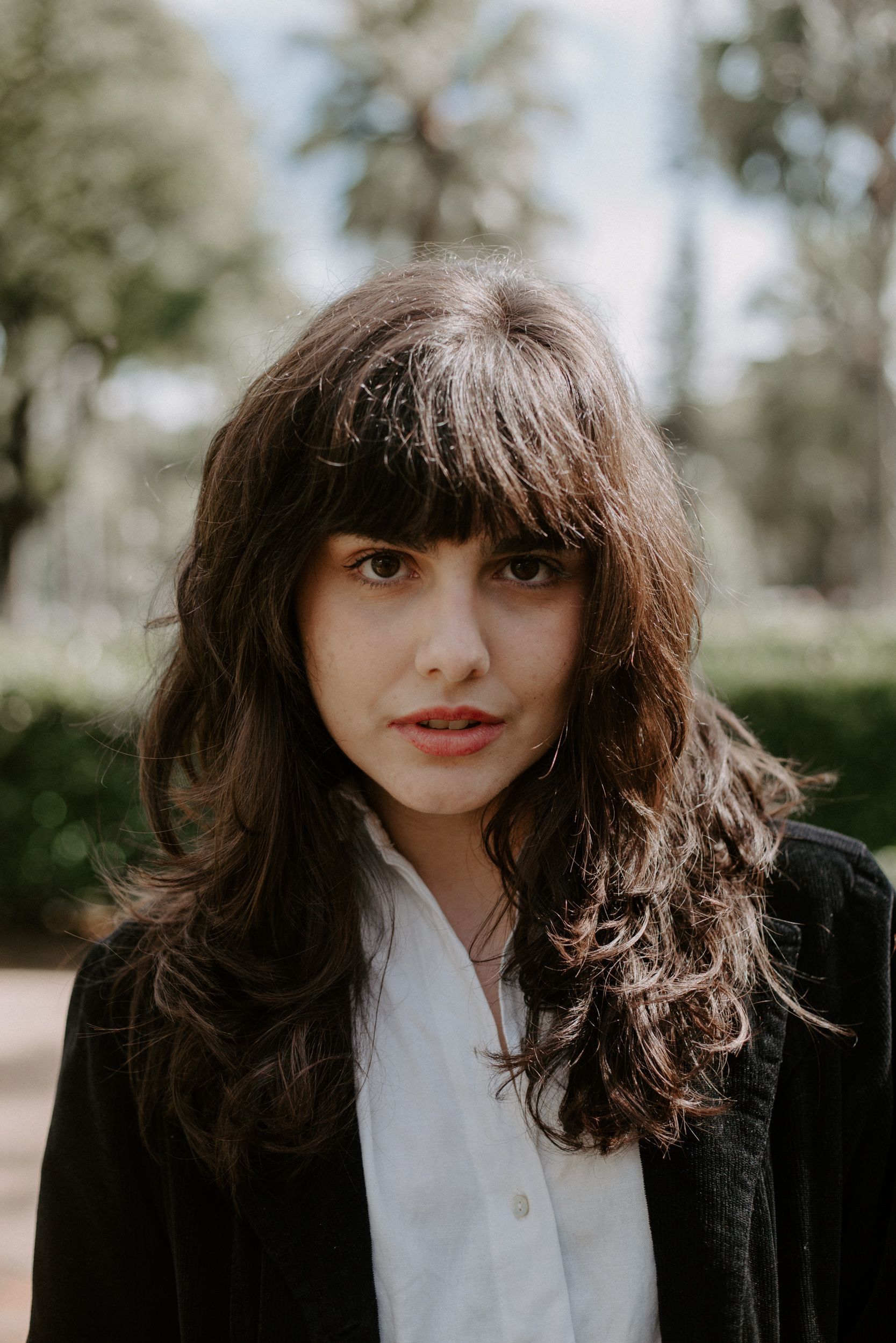 Charming portrait of a young woman with bangs outdoors in a park, Belo Horizonte, Brazil.